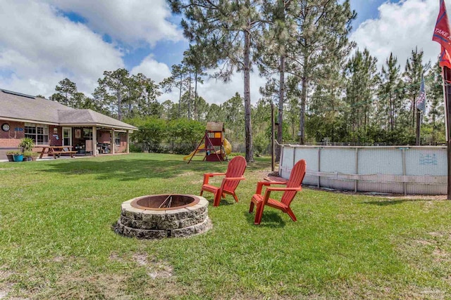 view of yard with a patio, a playground, a fire pit, and an outdoor pool