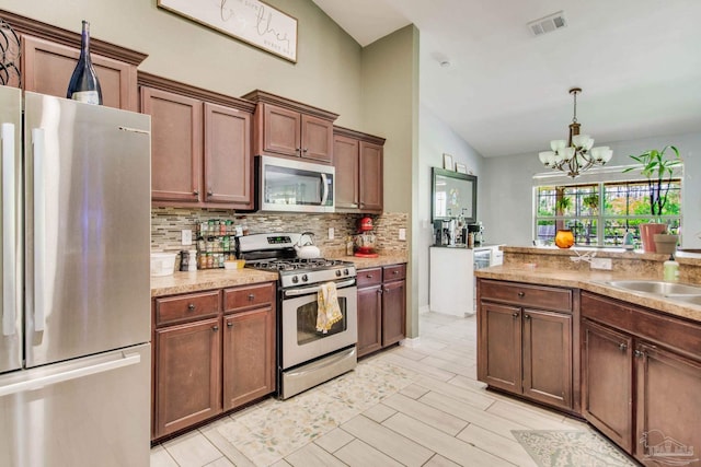 kitchen featuring backsplash, visible vents, appliances with stainless steel finishes, vaulted ceiling, and a notable chandelier