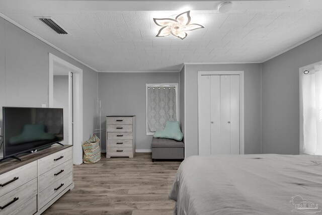 bedroom with a closet, crown molding, and hardwood / wood-style flooring