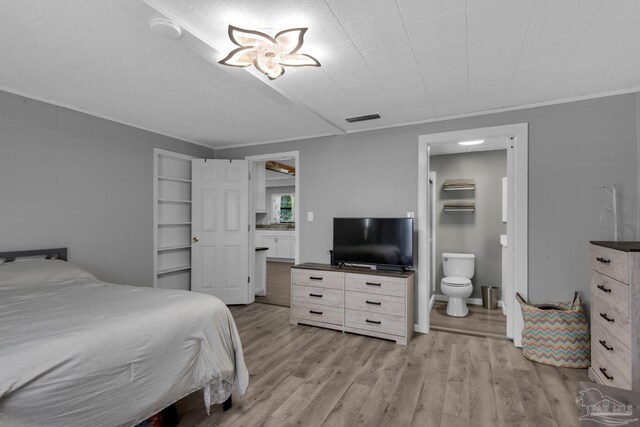 bedroom with light wood-type flooring, connected bathroom, and ornamental molding