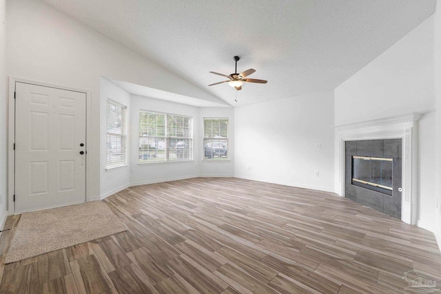 1042 Simpson St, Pensacola, FL 32526 - unfurnished living room with lofted ceiling, wood finished floors, ceiling fan, a tiled fireplace, and a textured ceiling