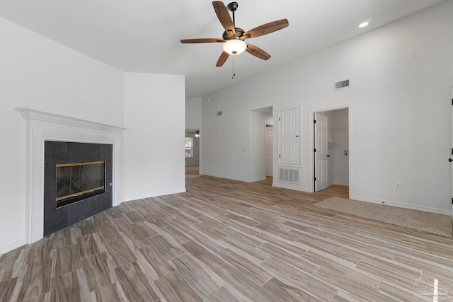 1042 Simpson St, Pensacola, FL 32526 - unfurnished living room with a ceiling fan, light wood finished floors, a towering ceiling, a tile fireplace, and baseboards