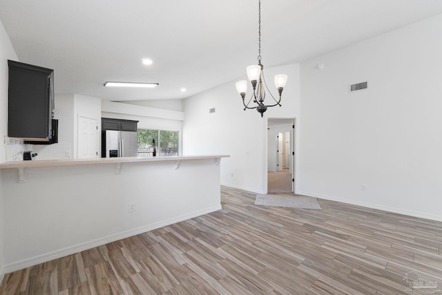 1042 Simpson St, Pensacola, FL 32526 - kitchen with stainless steel fridge with ice dispenser, light countertops, light wood-style floors, a chandelier, and a breakfast bar