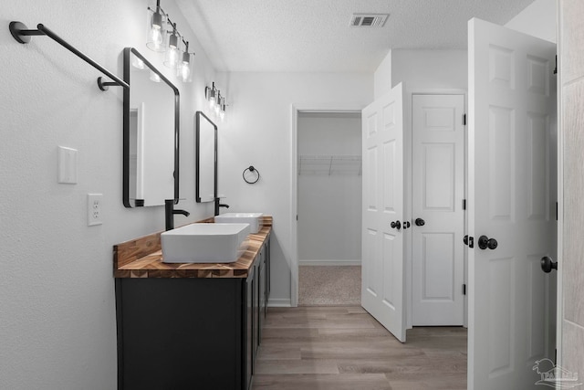 1042 Simpson St, Pensacola, FL 32526 - bathroom with wood finished floors, double vanity, a textured ceiling, and baseboards
