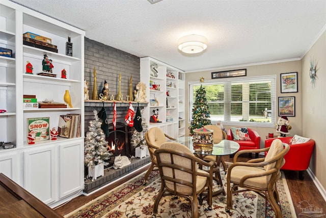 dining area featuring built in shelves, a textured ceiling, crown molding, hardwood / wood-style flooring, and a fireplace