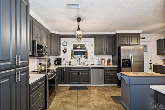 kitchen featuring tile patterned floors, sink, ornamental molding, appliances with stainless steel finishes, and decorative light fixtures