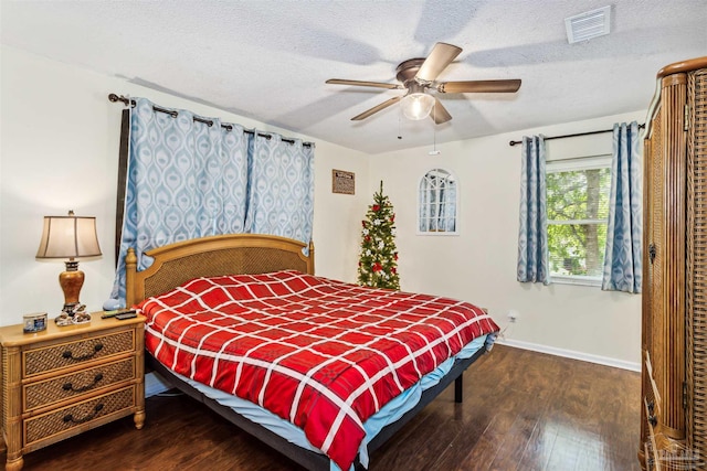 bedroom with ceiling fan, dark wood-type flooring, and a textured ceiling