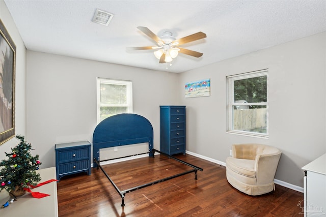 bedroom with a textured ceiling, ceiling fan, and dark wood-type flooring