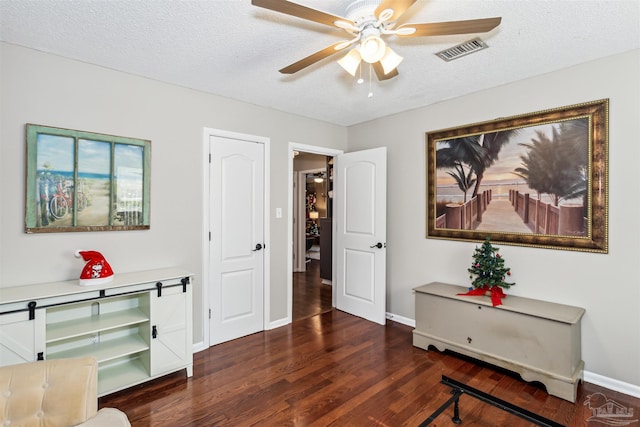 sitting room with dark hardwood / wood-style flooring, a textured ceiling, and ceiling fan