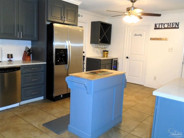 kitchen featuring crown molding, ceiling fan, light tile patterned floors, appliances with stainless steel finishes, and tasteful backsplash