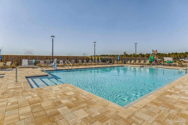 view of swimming pool featuring a playground and a patio area