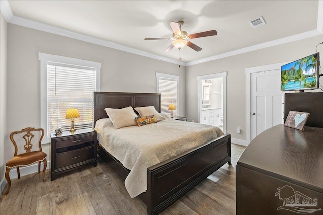 bedroom featuring ceiling fan, crown molding, wood-type flooring, and ensuite bath