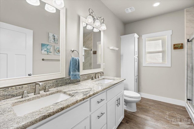 bathroom with toilet, hardwood / wood-style floors, walk in shower, and vanity