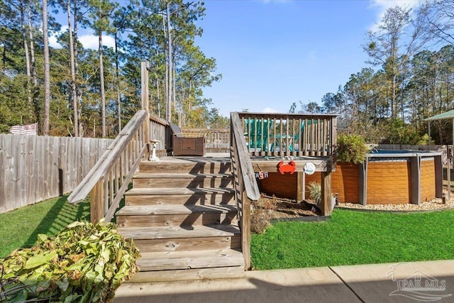 deck with a hot tub and a lawn