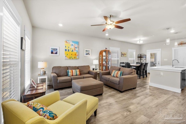 living room featuring ceiling fan, light hardwood / wood-style flooring, and sink