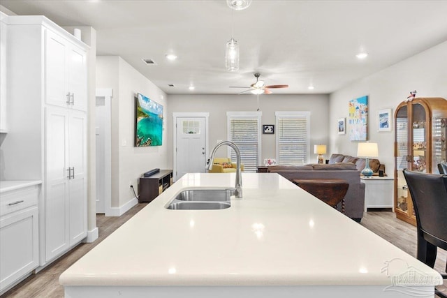 kitchen featuring an island with sink, white cabinets, ceiling fan, and sink