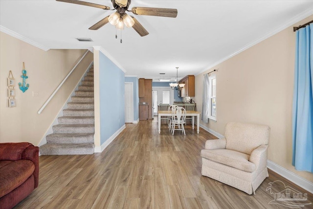 living room featuring crown molding, light hardwood / wood-style flooring, and ceiling fan with notable chandelier