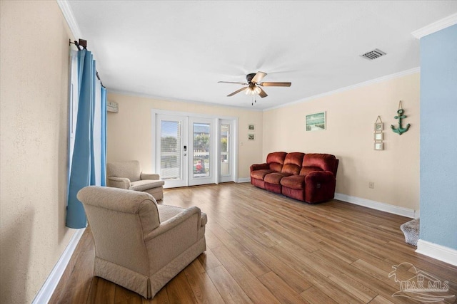 living room featuring wood-type flooring, ceiling fan, and crown molding