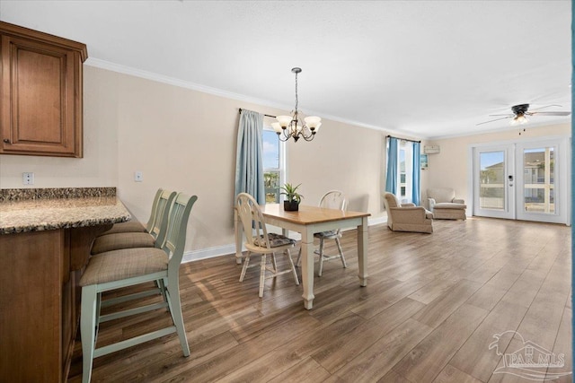 dining room with hardwood / wood-style flooring, ceiling fan with notable chandelier, crown molding, and french doors