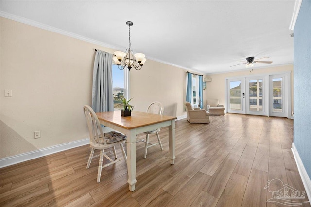 dining room with hardwood / wood-style floors, ceiling fan with notable chandelier, ornamental molding, and french doors