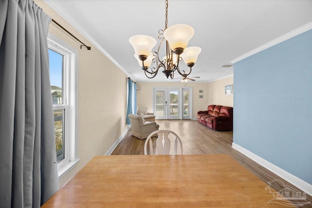 dining room with wood-type flooring, an inviting chandelier, french doors, and crown molding