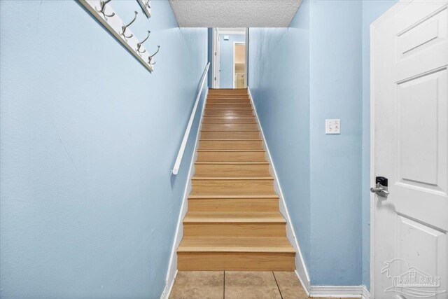 stairs featuring tile patterned flooring and a textured ceiling