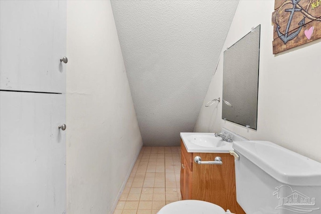 bathroom featuring tile patterned floors, vanity, toilet, and vaulted ceiling