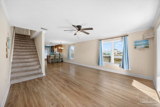 unfurnished living room featuring light hardwood / wood-style floors, ceiling fan with notable chandelier, and ornamental molding