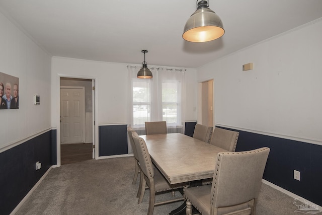 carpeted dining room featuring ornamental molding and a wainscoted wall