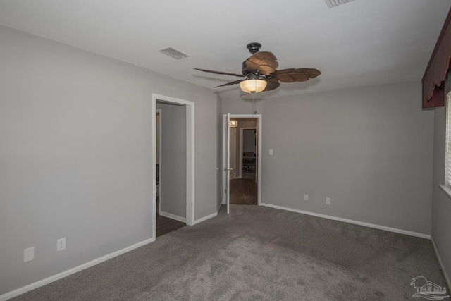 unfurnished room featuring a ceiling fan, visible vents, dark carpet, and baseboards