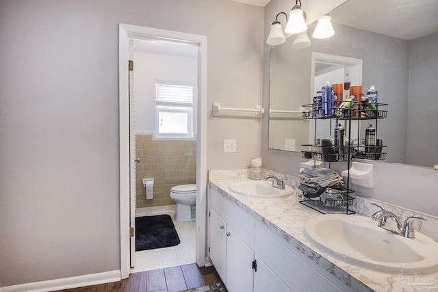 bathroom with wood finished floors, a sink, toilet, and double vanity