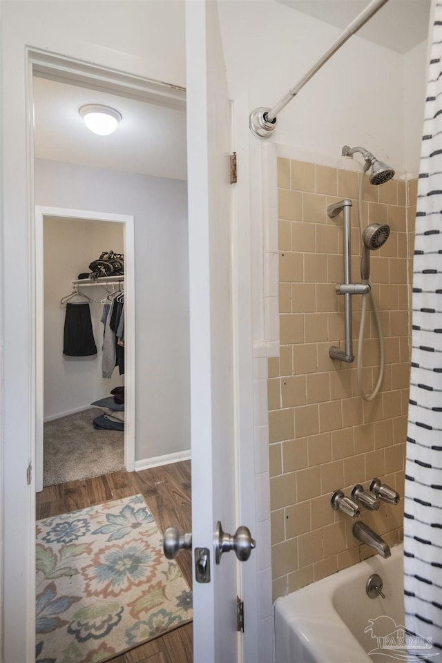 bathroom with shower / bathing tub combination, wood finished floors, and baseboards