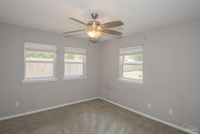 spare room featuring carpet floors, a wealth of natural light, baseboards, and a ceiling fan