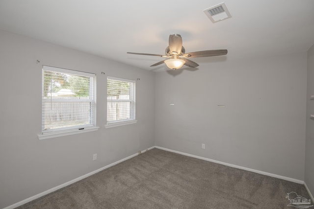 carpeted spare room featuring baseboards, visible vents, and ceiling fan