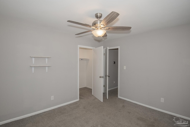 unfurnished bedroom with baseboards, ceiling fan, carpet, a walk in closet, and a closet