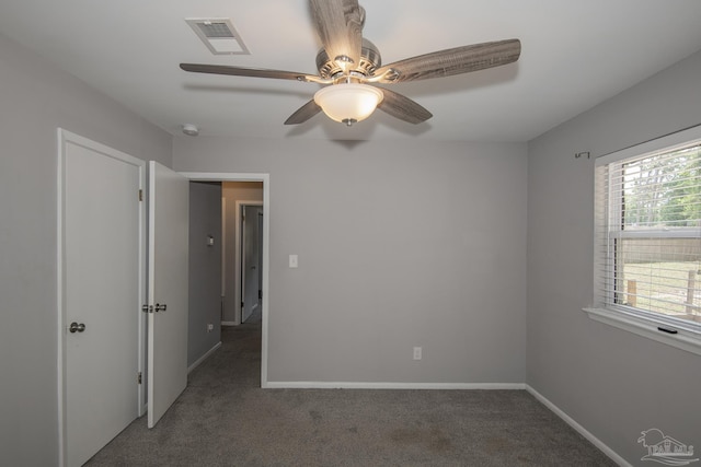 unfurnished bedroom featuring a ceiling fan, visible vents, dark carpet, and baseboards