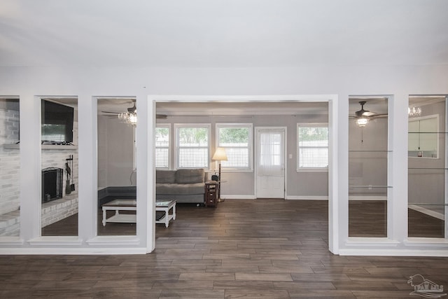 interior space featuring dark wood-type flooring, a fireplace, baseboards, and ceiling fan