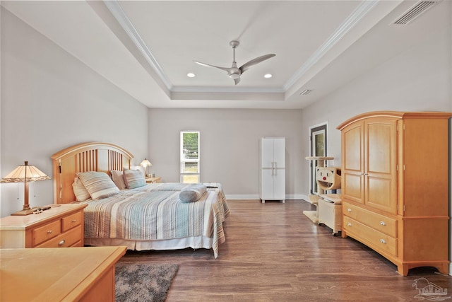 bedroom featuring recessed lighting, wood finished floors, ornamental molding, visible vents, and a tray ceiling