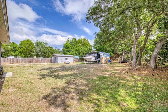 view of yard featuring an outbuilding, a shed, a carport, and fence