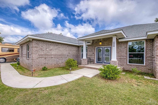 view of front of property with a front lawn, french doors, and brick siding