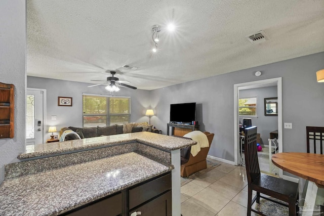 kitchen with a ceiling fan, a textured ceiling, visible vents, and light tile patterned flooring