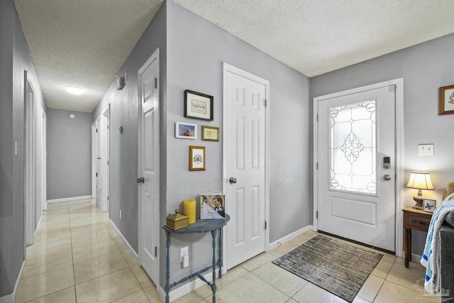 entryway with baseboards, a textured ceiling, and light tile patterned floors