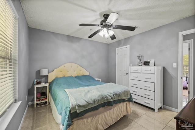 bedroom featuring light tile patterned flooring, a textured ceiling, and baseboards