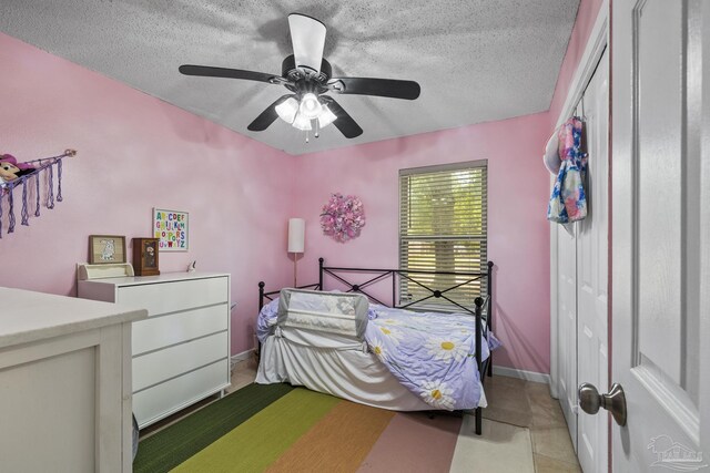 bedroom featuring light tile patterned flooring, a textured ceiling, and ceiling fan