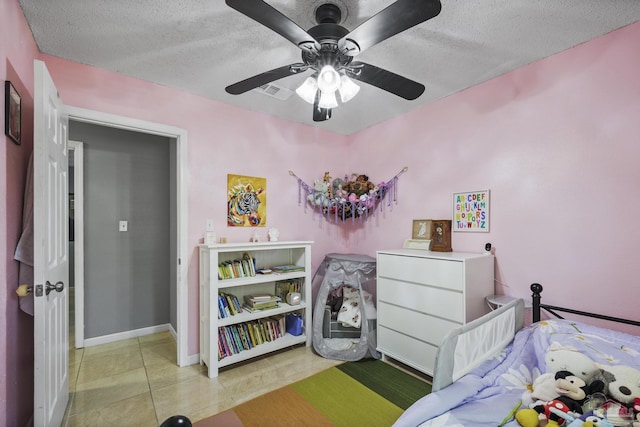 bedroom with ceiling fan, a textured ceiling, visible vents, baseboards, and light tile patterned flooring