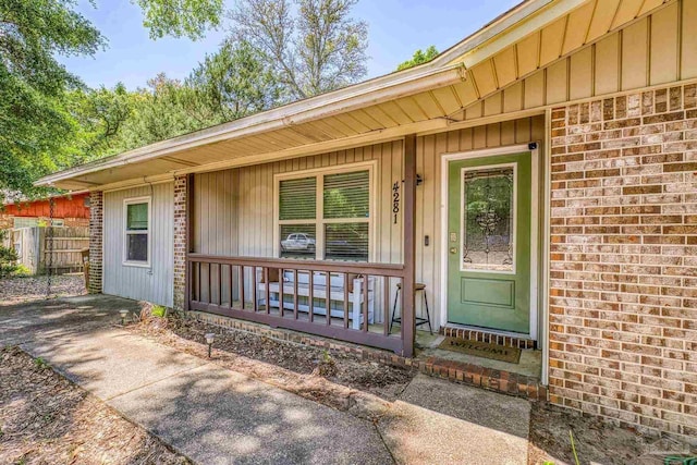 entrance to property featuring brick siding, board and batten siding, and covered porch