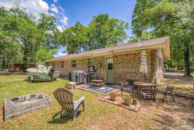 back of property featuring brick siding, a yard, and a patio