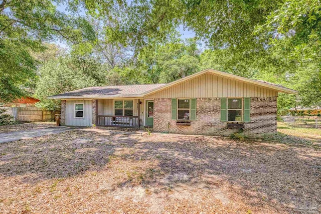 ranch-style home with fence, covered porch, and brick siding