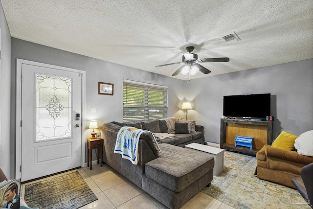living room featuring light tile patterned floors, ceiling fan, a textured ceiling, and visible vents