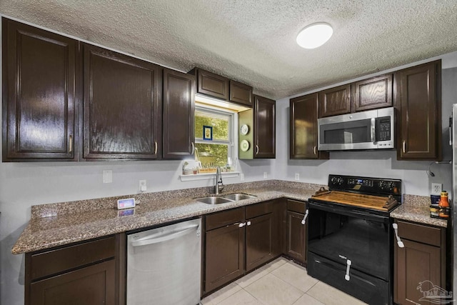kitchen with a textured ceiling, dark brown cabinets, a sink, stainless steel appliances, and light tile patterned flooring